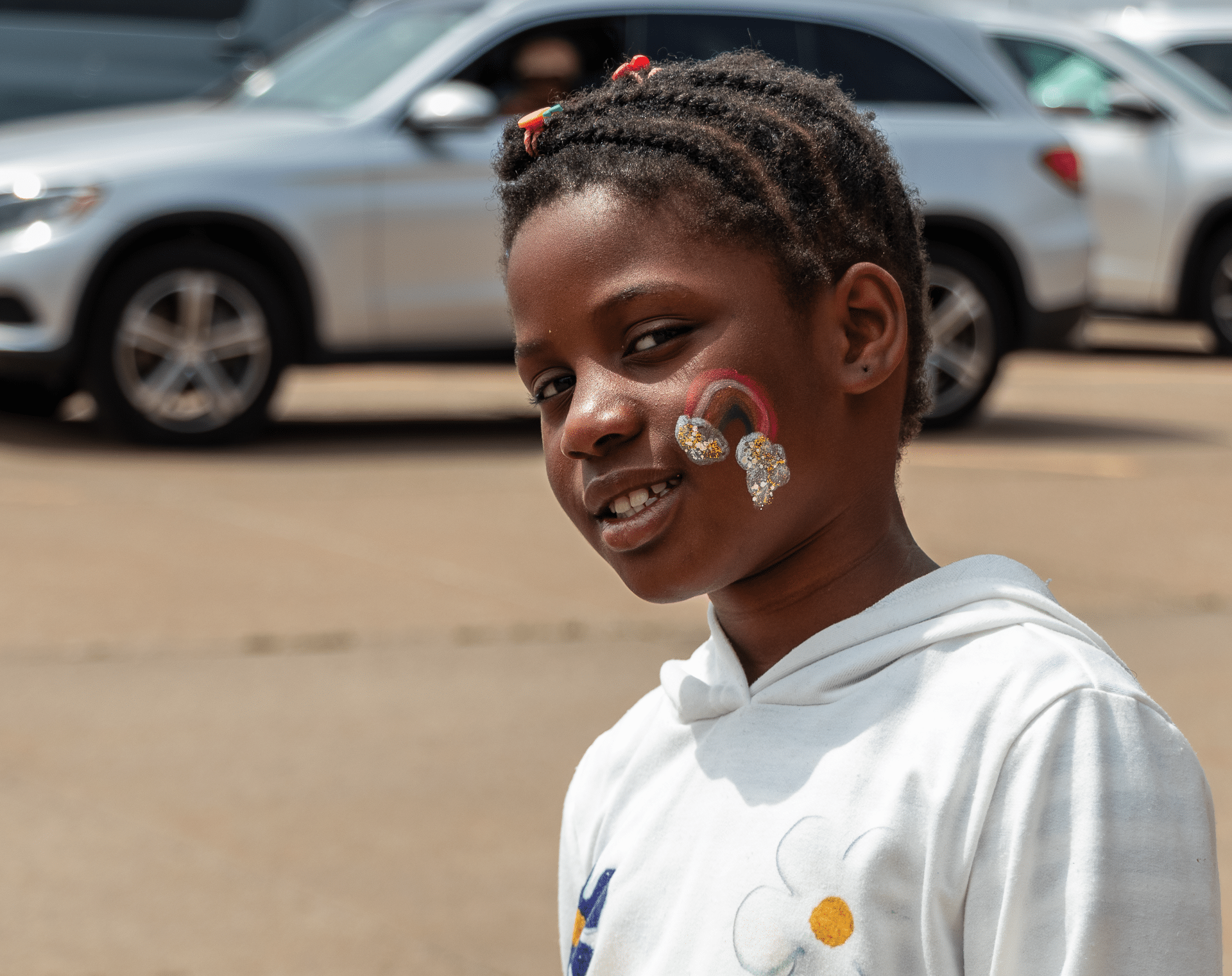 A smiling child with a rainbow-painted cheek enjoys our church gathering—where everyone is welcome and hope blossoms. - Muscatine Church of Christ