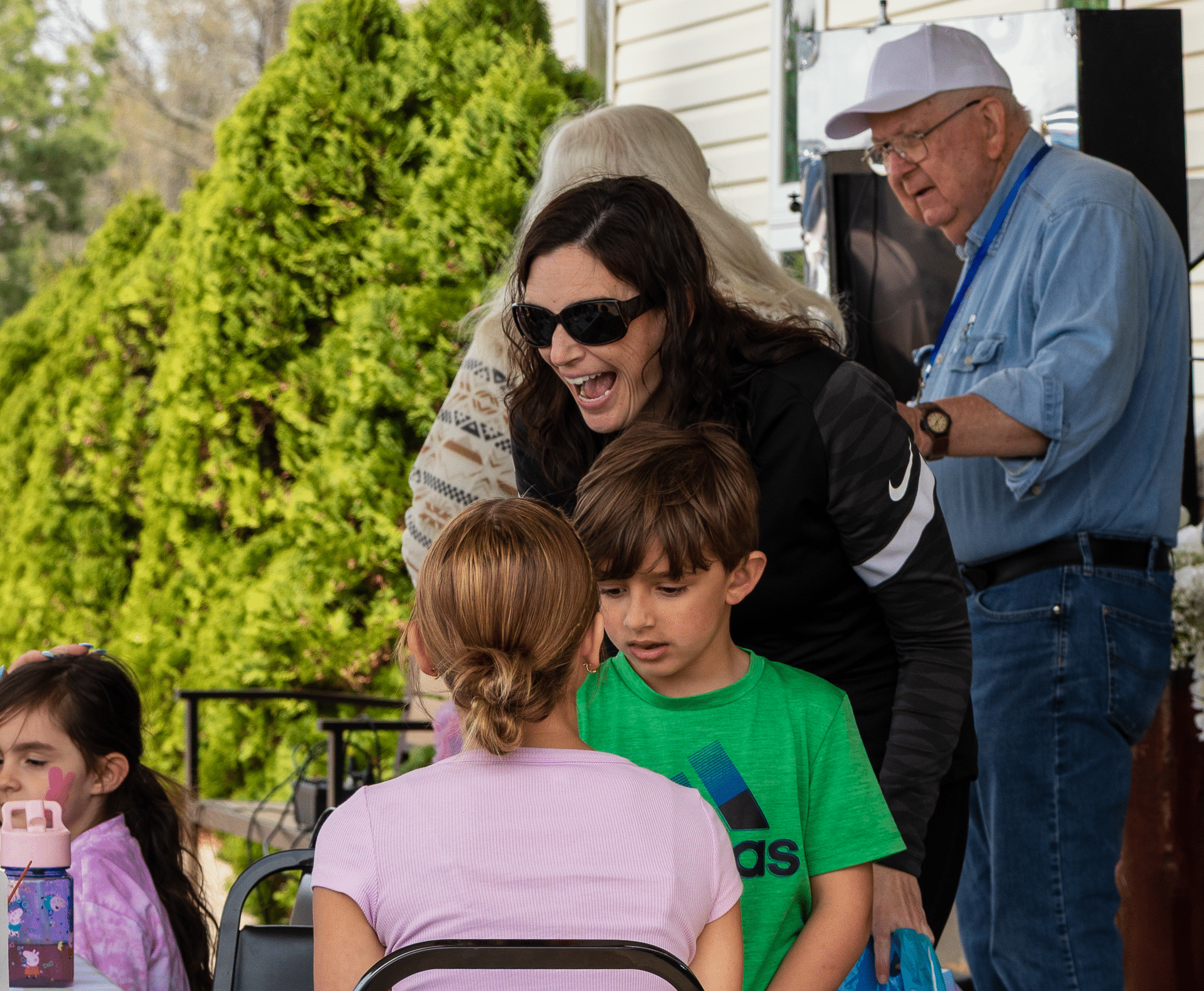 A woman warmly chats with two children at an outdoor table, surrounded by friendly faces and caring community. - Muscatine Church of Christ