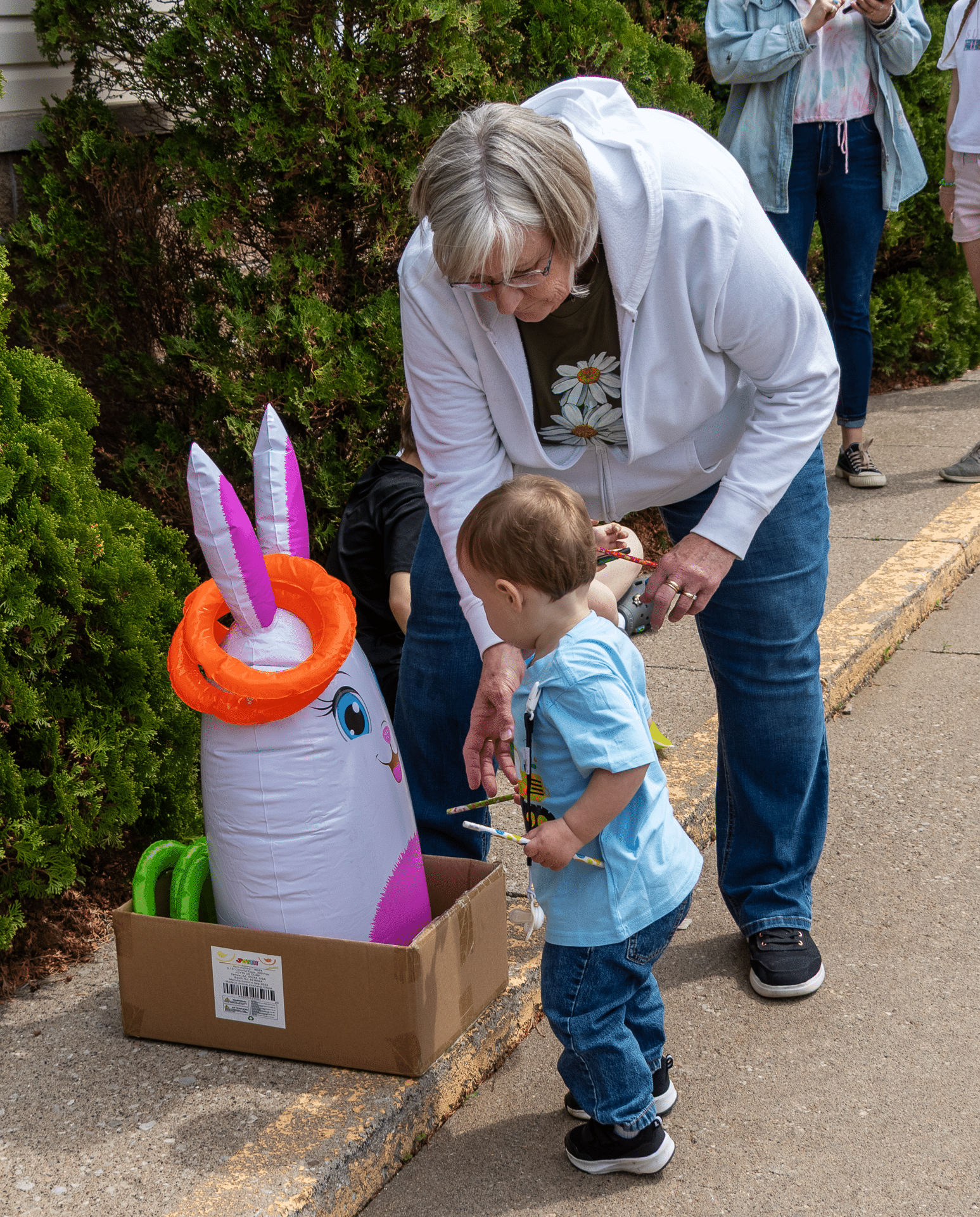 An older woman and a child share smiles by a cheerful bunny toy, welcoming all to our church family. - Muscatine Church of Christ
