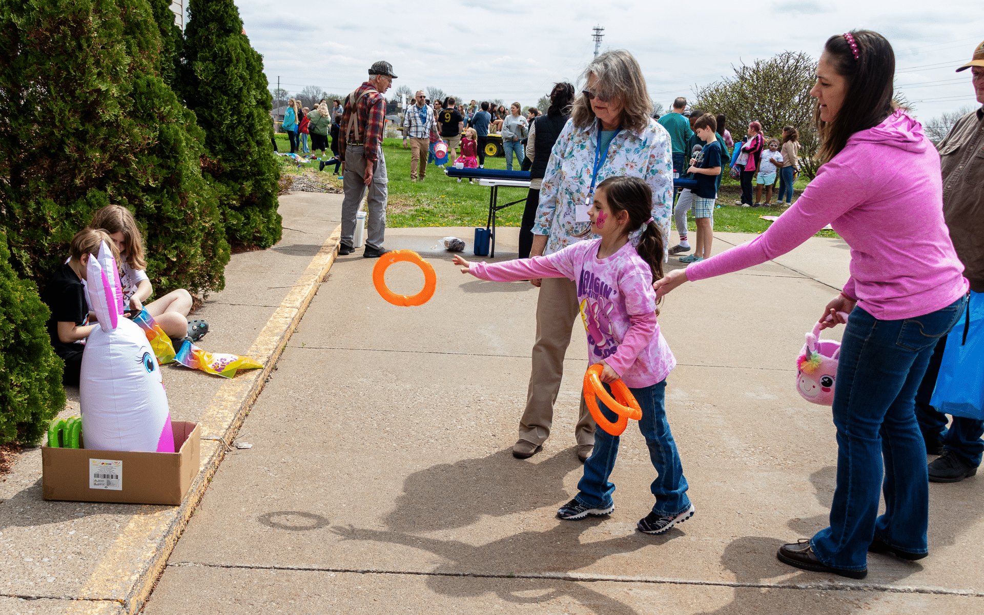 A young girl plays ring toss with a unicorn as families gather, sharing joy, laughter, and hope in our community. - Muscatine Church of Christ