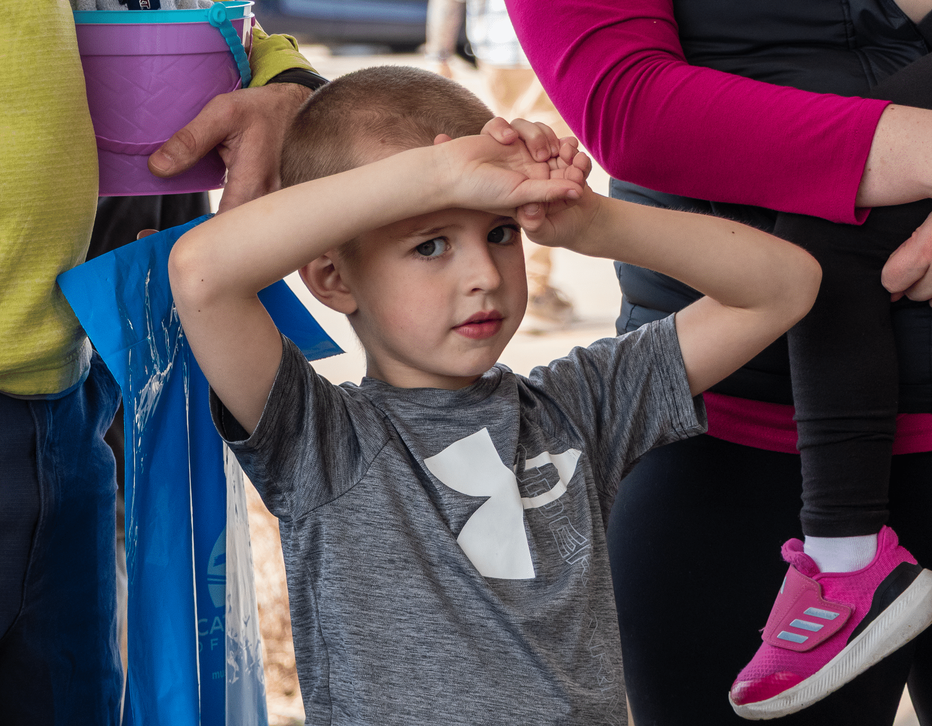 A young boy joyfully lifts his arms, surrounded by caring adults—celebrating community and hope together. - Muscatine Church of Christ