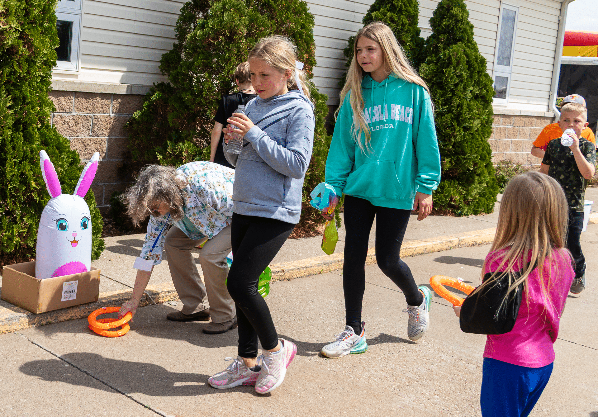 Kids and an older friend share smiles as they play ring toss together outside, spreading joy and hope in our community. - Muscatine Church of Christ