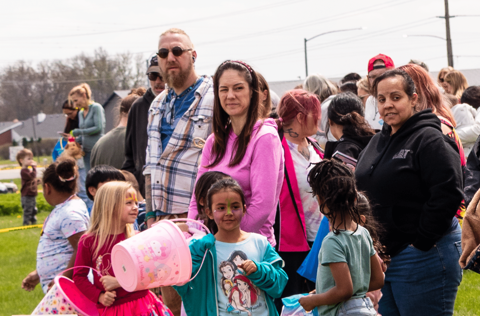 Smiling adults and kids gather on the grass with colorful buckets—celebrating hope, joy, and community together. - Muscatine Church of Christ