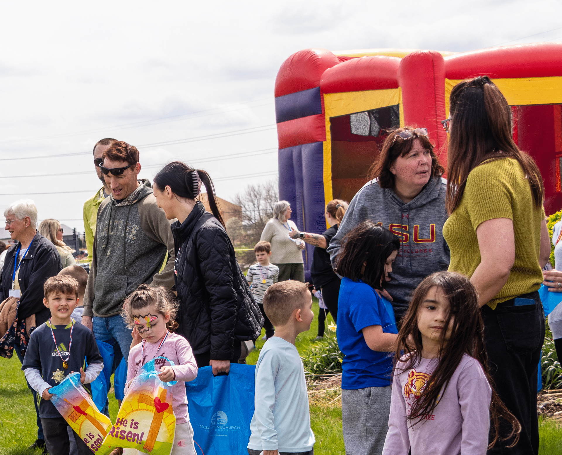 Families and kids smiling together by a bright bounce house—celebrating community, joy, and hope at Muscatine Church of Christ. - Muscatine Church of Christ