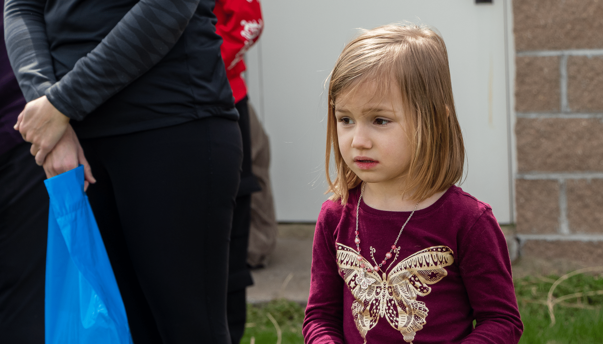 A young girl stands among caring adults outside, welcomed into our hopeful, loving church community. - Muscatine Church of Christ