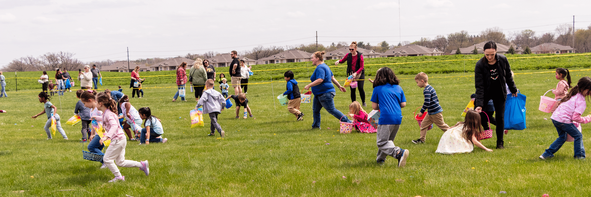 Kids enjoy an outdoor egg hunt on the grass as caring adults look on—celebrating joy, community, and hope together. - Muscatine Church of Christ