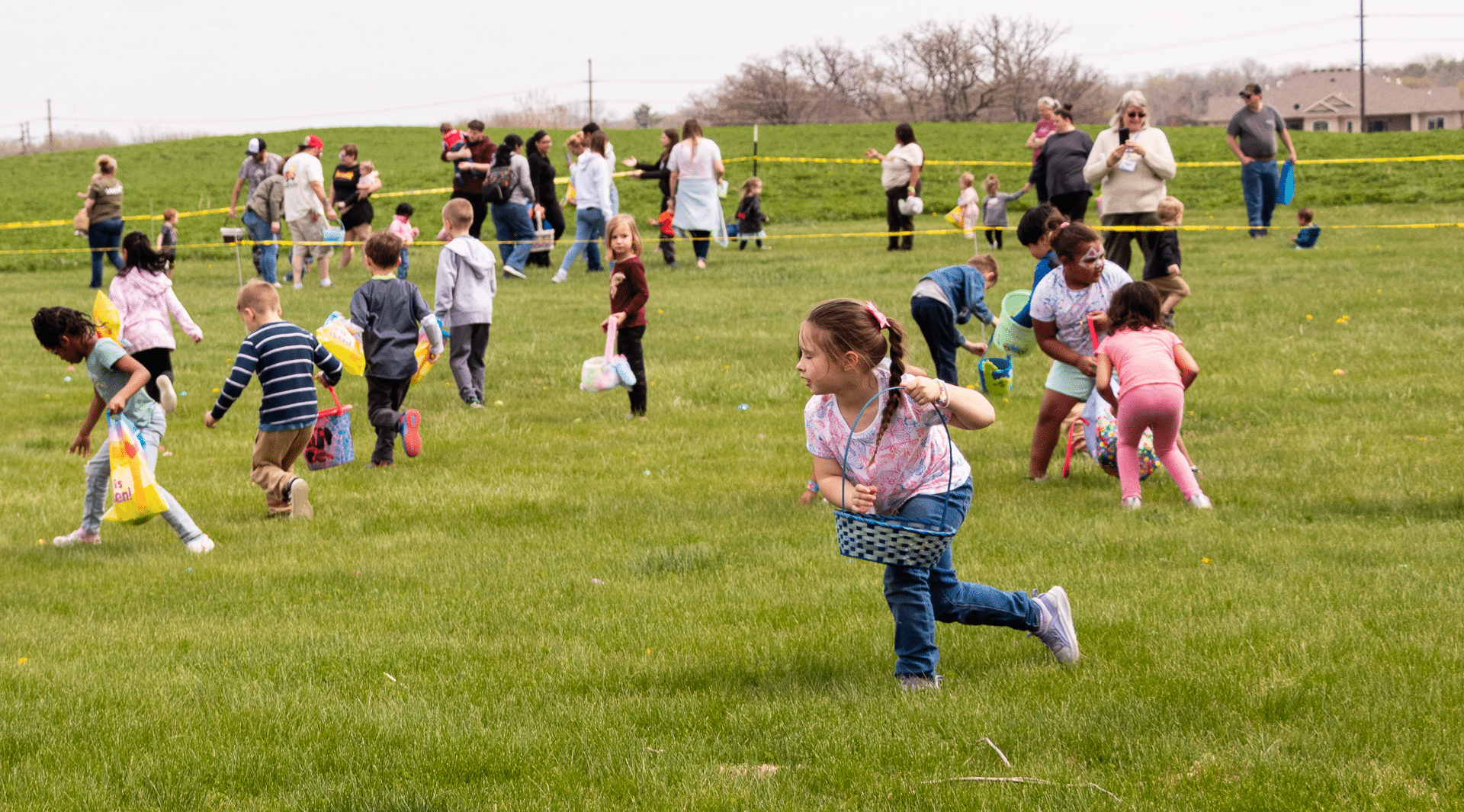 Children joyfully hunt for eggs on the grass as caring adults cheer them on, sharing hope and community together. - Muscatine Church of Christ