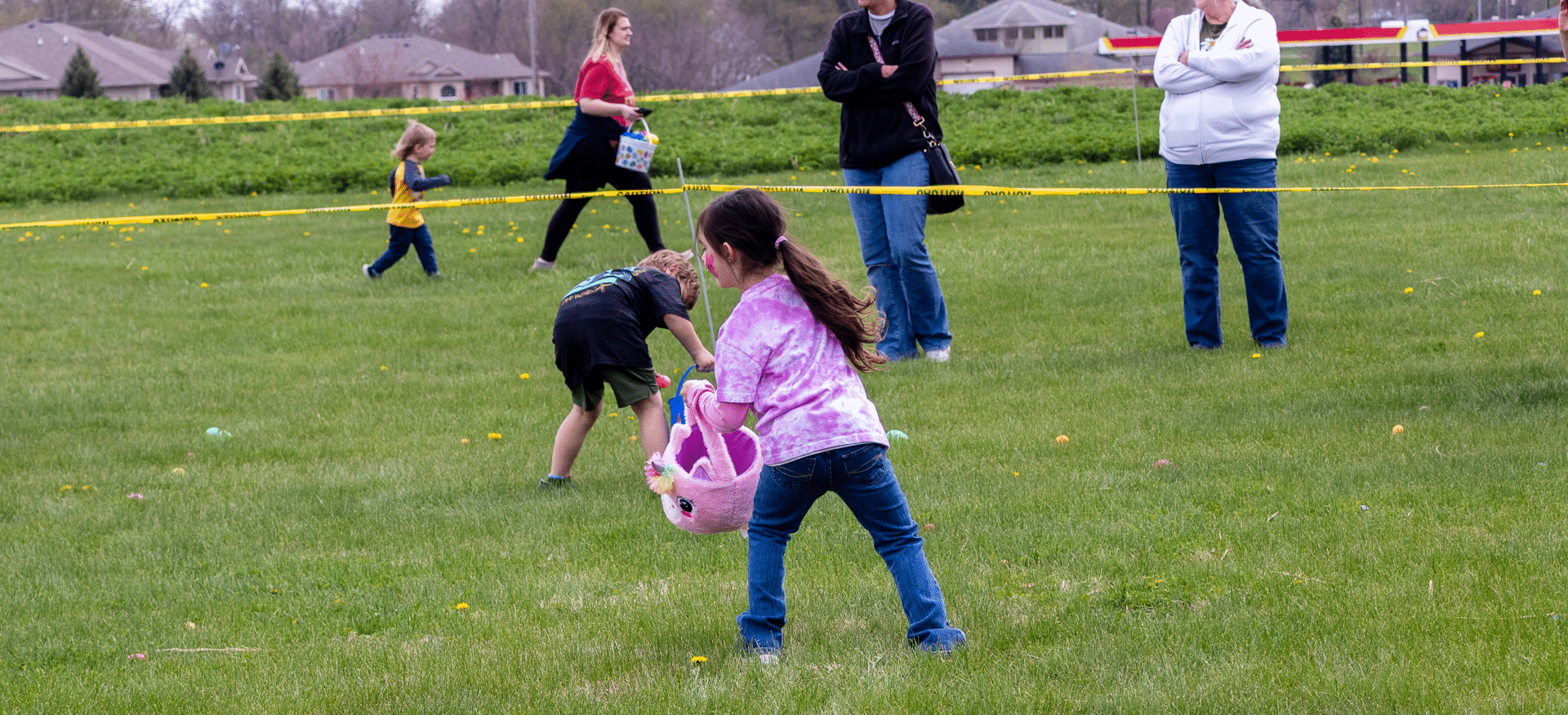 Children joyfully hunt for eggs on a sunny lawn as families gather, sharing laughter, hope, and warm fellowship. - Muscatine Church of Christ