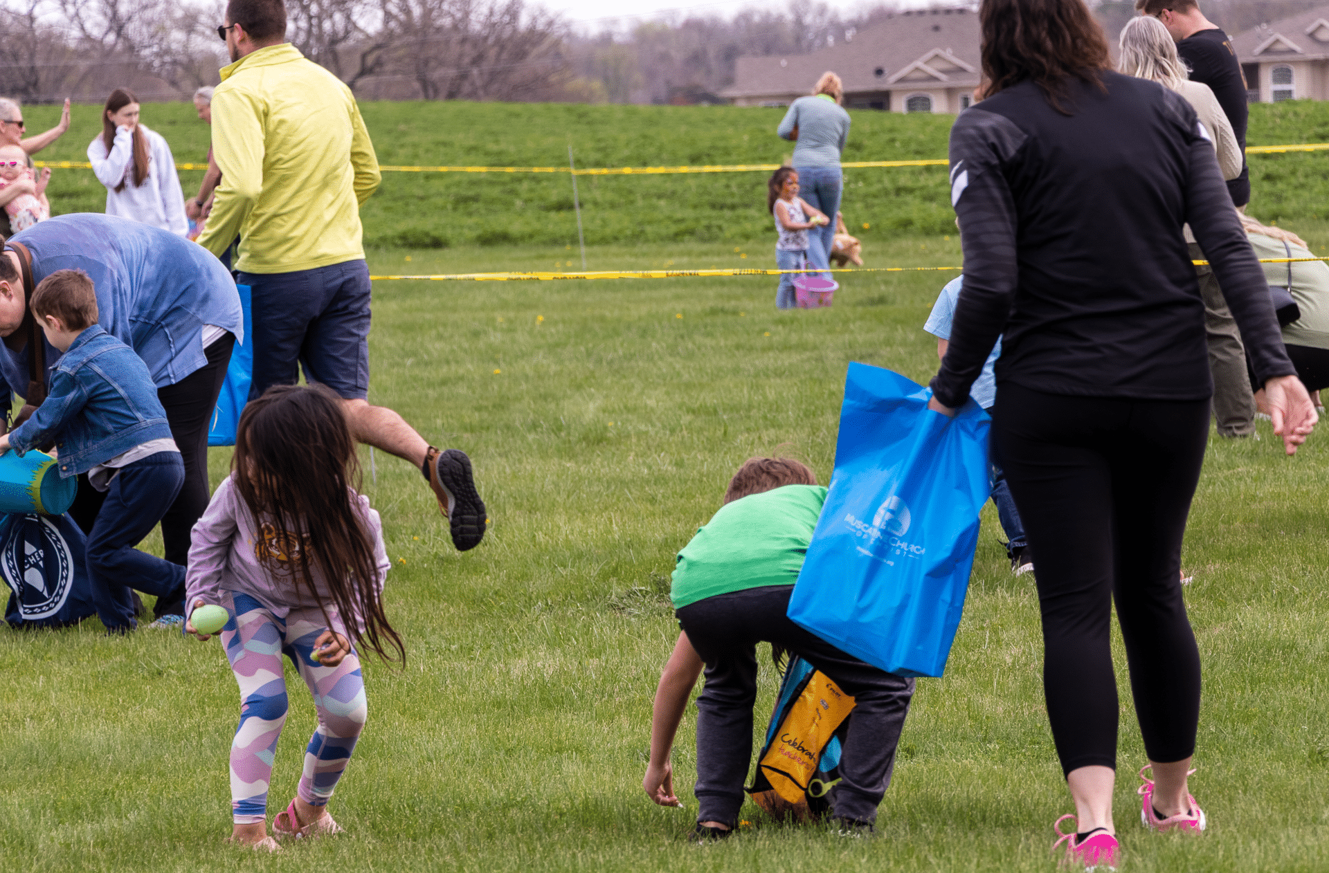 Families and friends joyfully hunt for eggs together on a sunny lawn, sharing laughter, hope, and community. - Muscatine Church of Christ