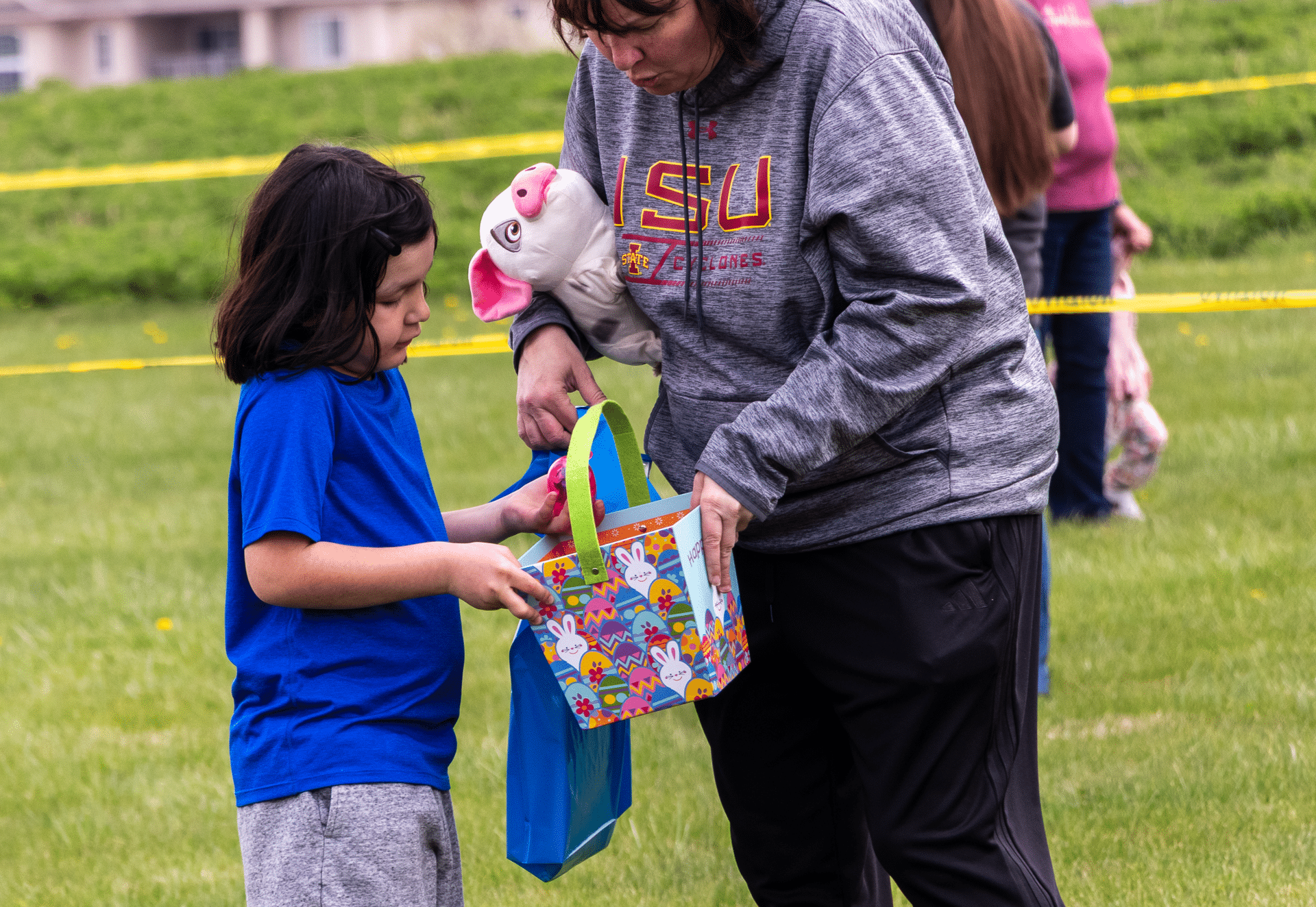 An adult and child share a joyful Easter moment, filling a bright basket together—celebrating hope and community. - Muscatine Church of Christ