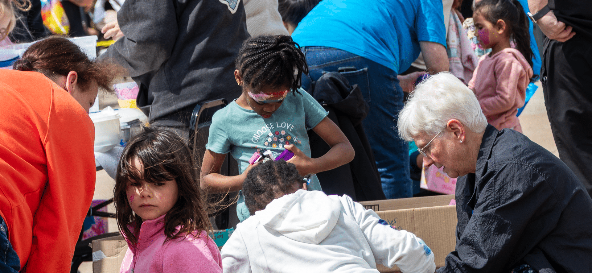 Families and friends of all ages share joyful activities outdoors, painting faces and building hope together. - Muscatine Church of Christ