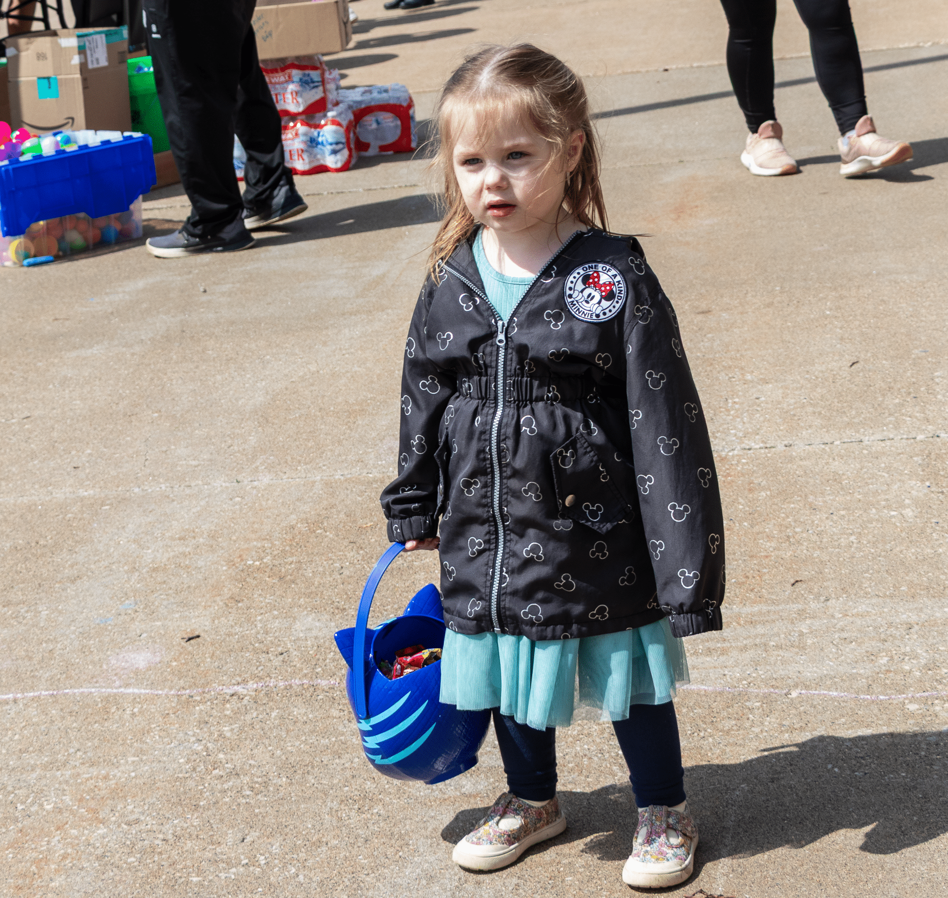 A smiling girl in a blue dress holds a basket outside, ready to share joy and hope with our church family. - Muscatine Church of Christ