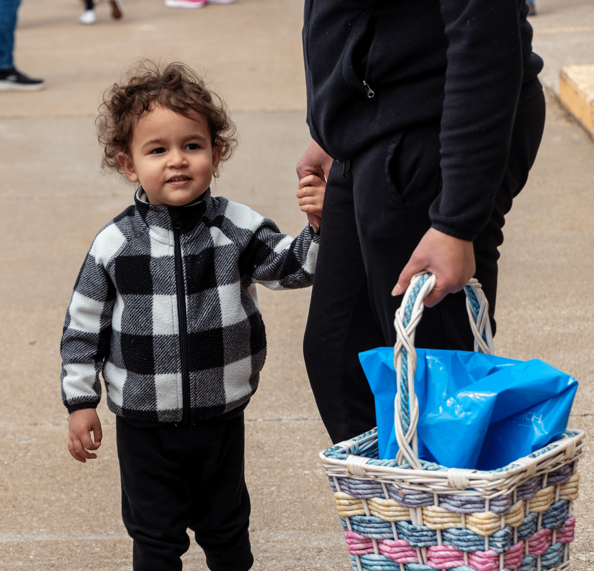 Child holding an adults hand by a basket outdoors—welcomed together in faith, hope, and community. - Muscatine Church of Christ