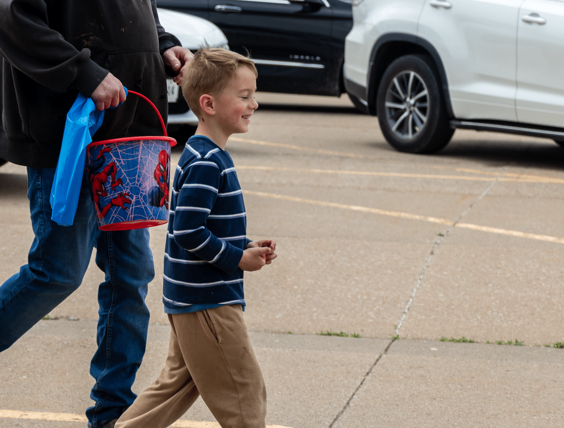 A child with a Spider-Man bucket walks hand-in-hand with an adult—sharing hope, welcome, and community with us. - Muscatine Church of Christ