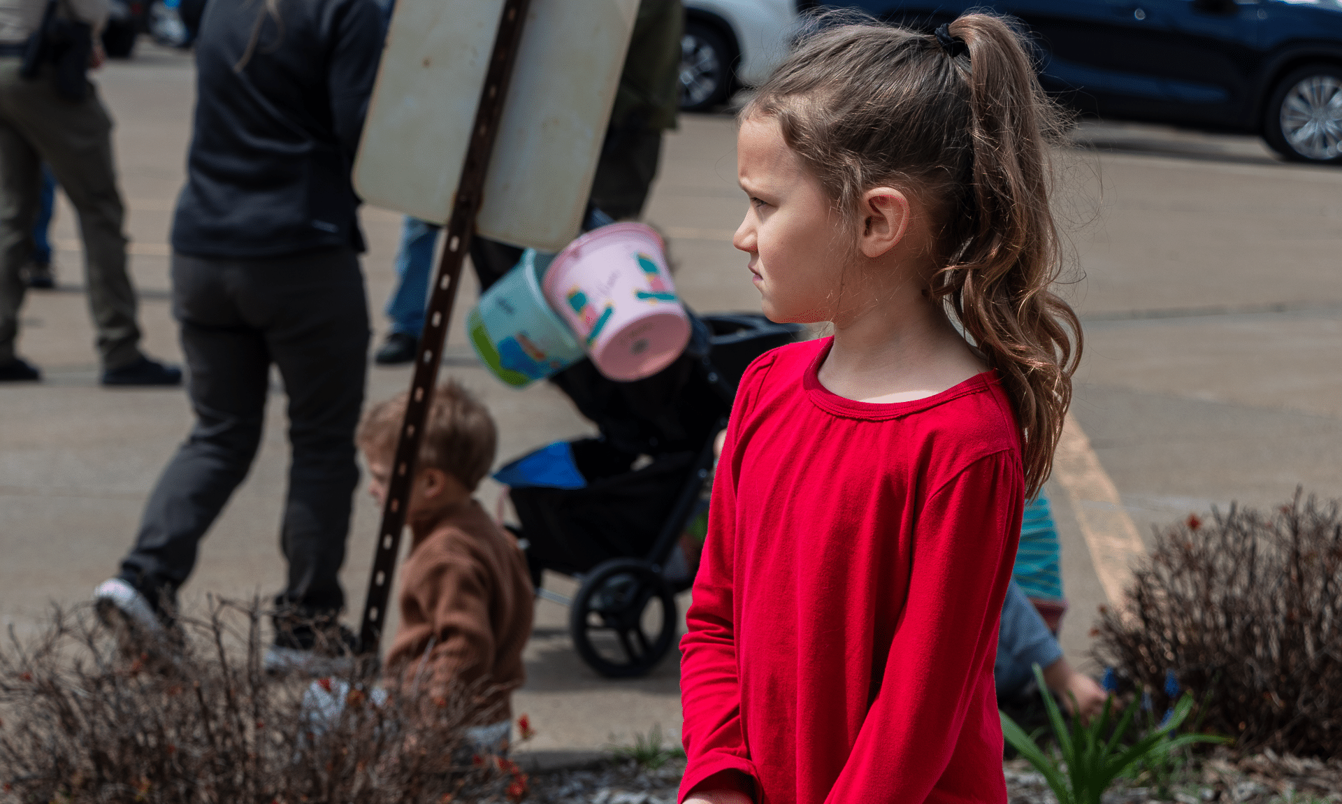A young girl stands outside among friends in a parking lot, surrounded by warmth, hope, and our caring church family. - Muscatine Church of Christ